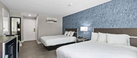A hotel room with two beds, a desk, and a mirror.