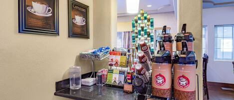 Una estación de café con opciones de espresso y capuchino, una cafetera y una exhibición de paquetes de café.