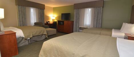 Een hotelkamer met twee bedden, een bureau, een stoel, een televisie en een lamp.