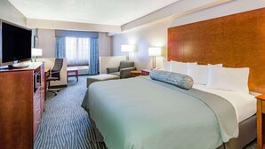 Een hotelkamer met een groot bed, een bureau met televisie, een stoel en twee lampen.