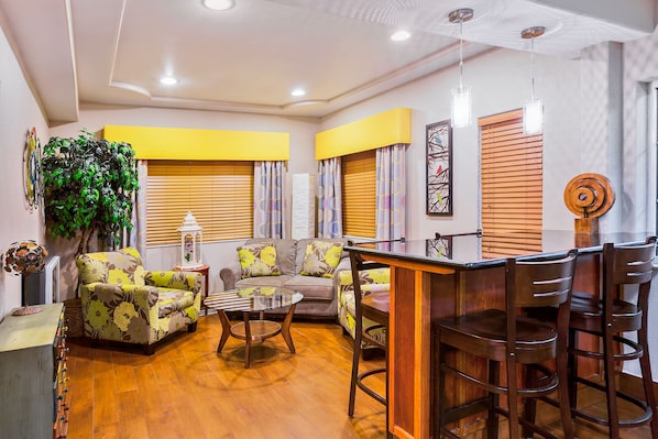 A living room with a sofa, a coffee table, and a dining area with chairs.