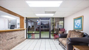 A reception area with a reception desk, a leather sofa, and a small table. - Super 8 by Wyndham Clinton (Clinton)