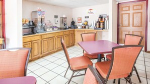 A breakfast area with a counter, coffee machines, and seating. - Super 8 by Wyndham Clinton (Clinton)