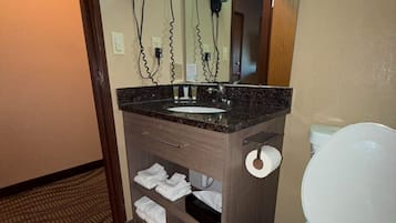 Un baño con lavamanos de mármol, inodoro y toallero.