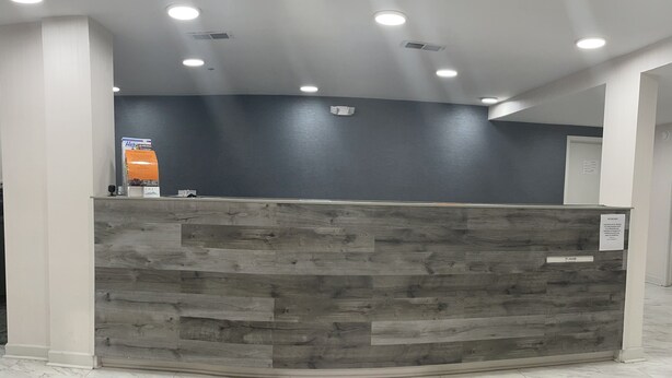 A reception desk with a grey wooden panel, white pillars, and a marble floor. - Griffin Inn and Suites (Griffin)