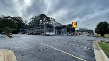 Un motel amb zona de pàrquing coberta i edifici amb balcó.