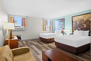 A hotel room with a large bed, a smaller bed, a desk, a chair, and a couch. There is a window with curtains, a wall-mounted air conditioner, and a painting on the wall. - Super 8 by Wyndham Thunder Bay (Thunder Bay)