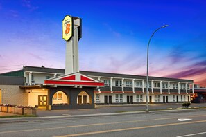 A motel with a prominent 'Super 8' sign, a central entrance with an archway, and a row of rooms with balconies.