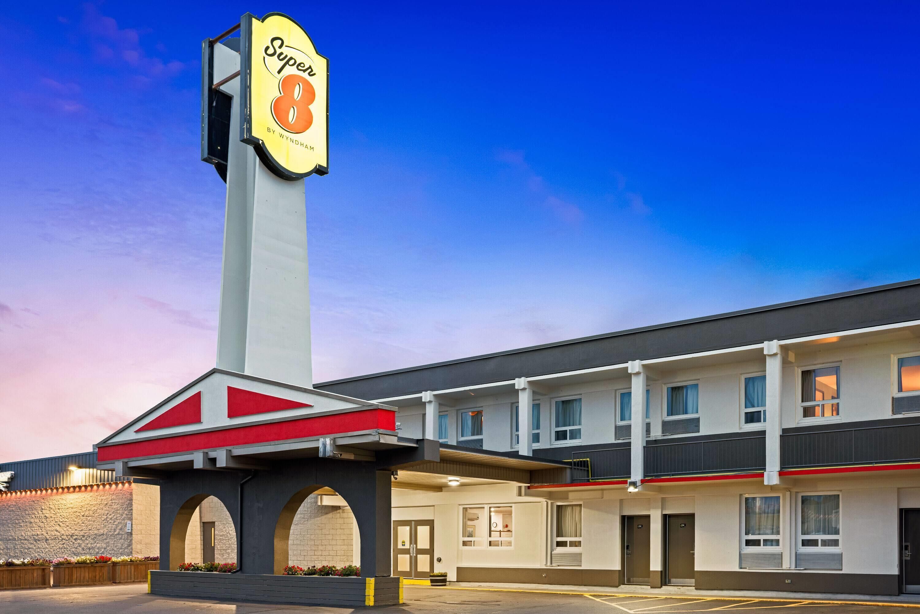 Un hôtel reconnaissable à son grand panneau « Super 8 », un bâtiment à deux étages et un parking.