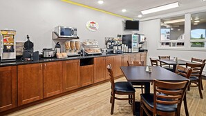 A breakfast area with a counter, coffee machines, and seating.