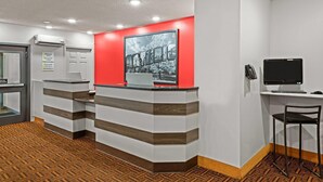 A reception area with a red accent wall, a reception desk, a computer monitor, and a chair.