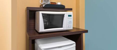 Una kitchenette compacta equipada con microondas, cafetera y refrigerador pequeño.