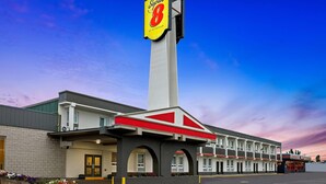 A Super 8 motel with a prominent sign, a parking lot, and a row of rooms with a central entrance.