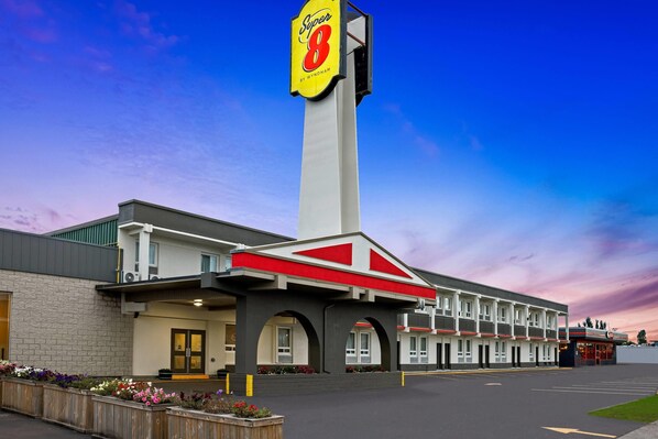 A Super 8 motel with a prominent sign, a parking lot, and a row of rooms with a central entrance.