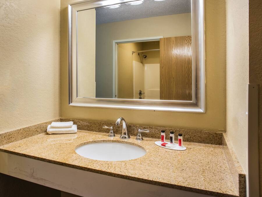 Un baño con encimera de granito, un lavabo blanco, un espejo y una toalla.