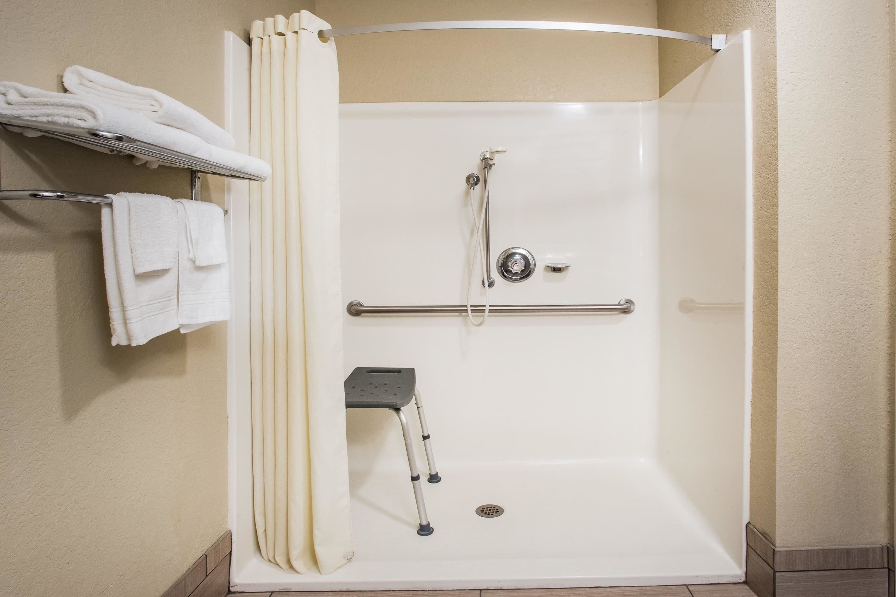 Eine bodengleiche Dusche mit Haltegriff, Handtuchhalter und Duschsitz.