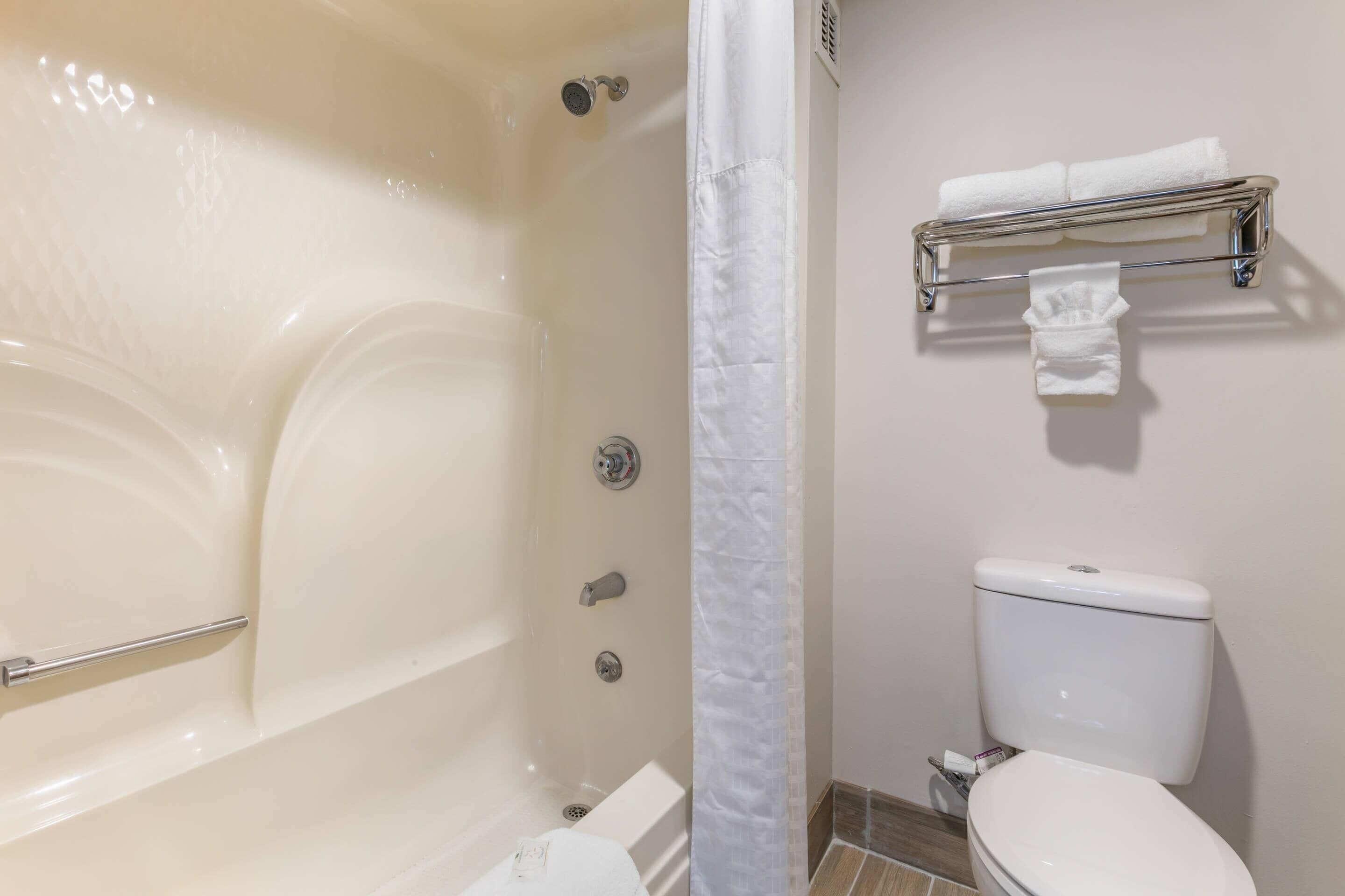 A bathroom with a bathtub, toilet, and a towel rack.