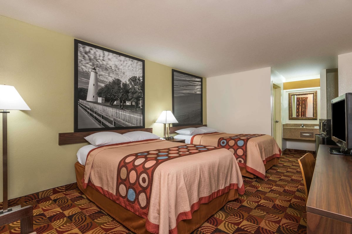 Habitación de hotel con dos camas, televisión, escritorio y un cuadro grande en la pared.