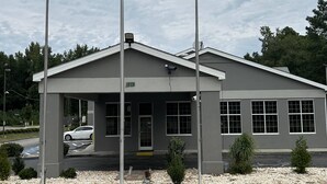 A building with a grey facade, large windows, and a covered entrance. - Super 8 by Wyndham Fayetteville (Fayetteville)