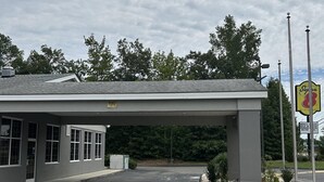 A building with a covered parking area, a signboard, and a fenced entrance. - Super 8 by Wyndham Fayetteville (Fayetteville)