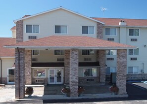 Un hotel de dos pisos con entrada techada, pilares de ladrillo y techo rojo.