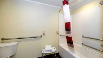 Un baño con inodoro, ducha con cortina roja y blanca, y un taburete pequeño y blanco.