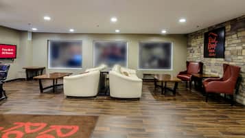 Un hall de hotel con zonas de estar, un televisor y un cartel de Red Roof Inn.