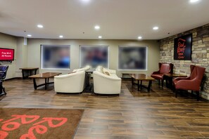 A hotel lobby with seating areas, a television, and a sign for Red Roof Inn. - Red Roof Inn Osage Beach - Lake of the Ozarks (Osage Beach)
