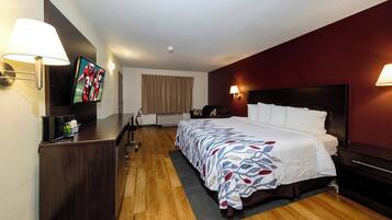 A hotel room with a bed, a desk, a television, and a window with curtains.