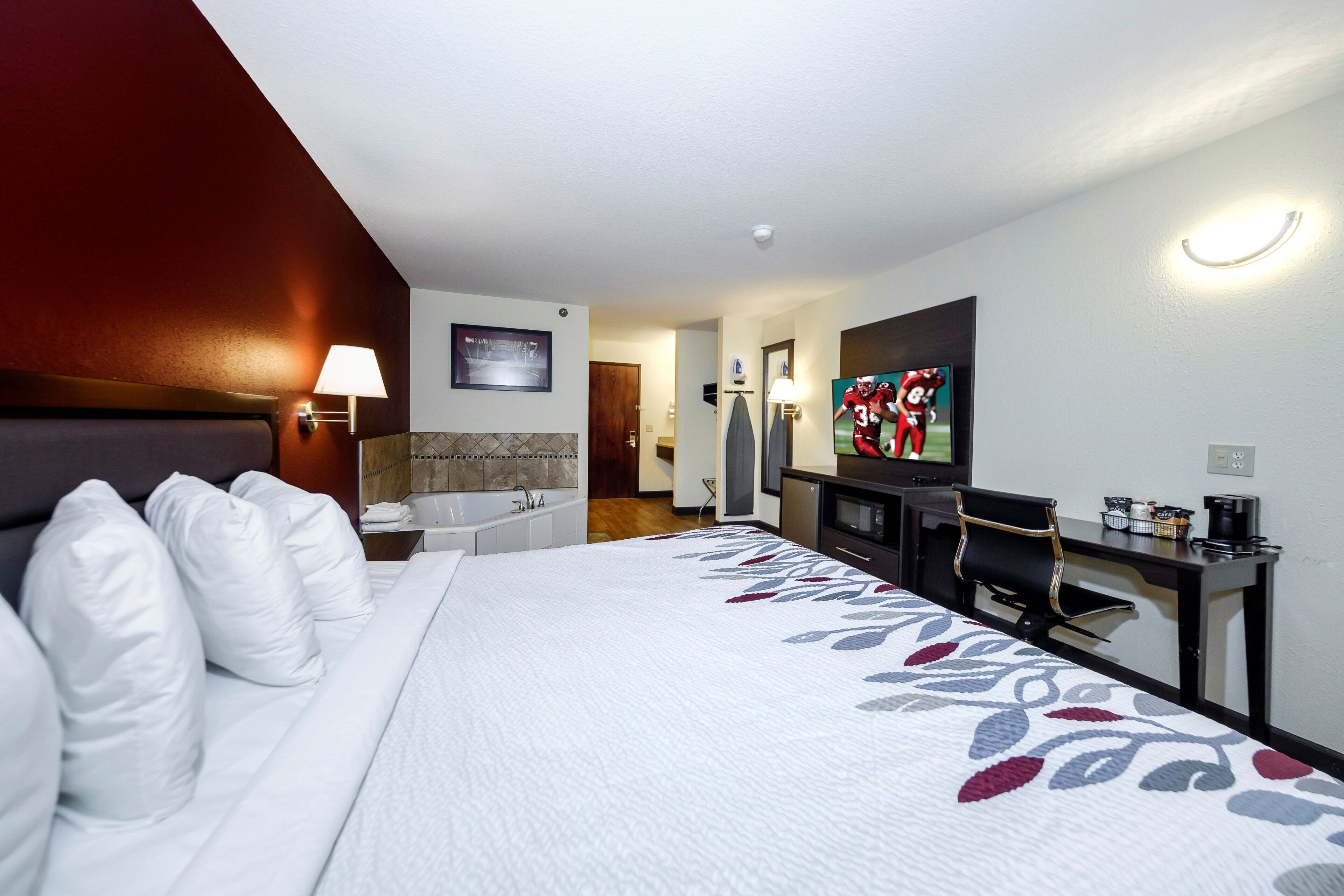 Una habitación de hotel con cama, escritorio, televisor y baño.