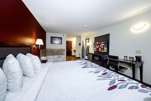 A hotel room with a bed, a desk, a television, and a bathroom.