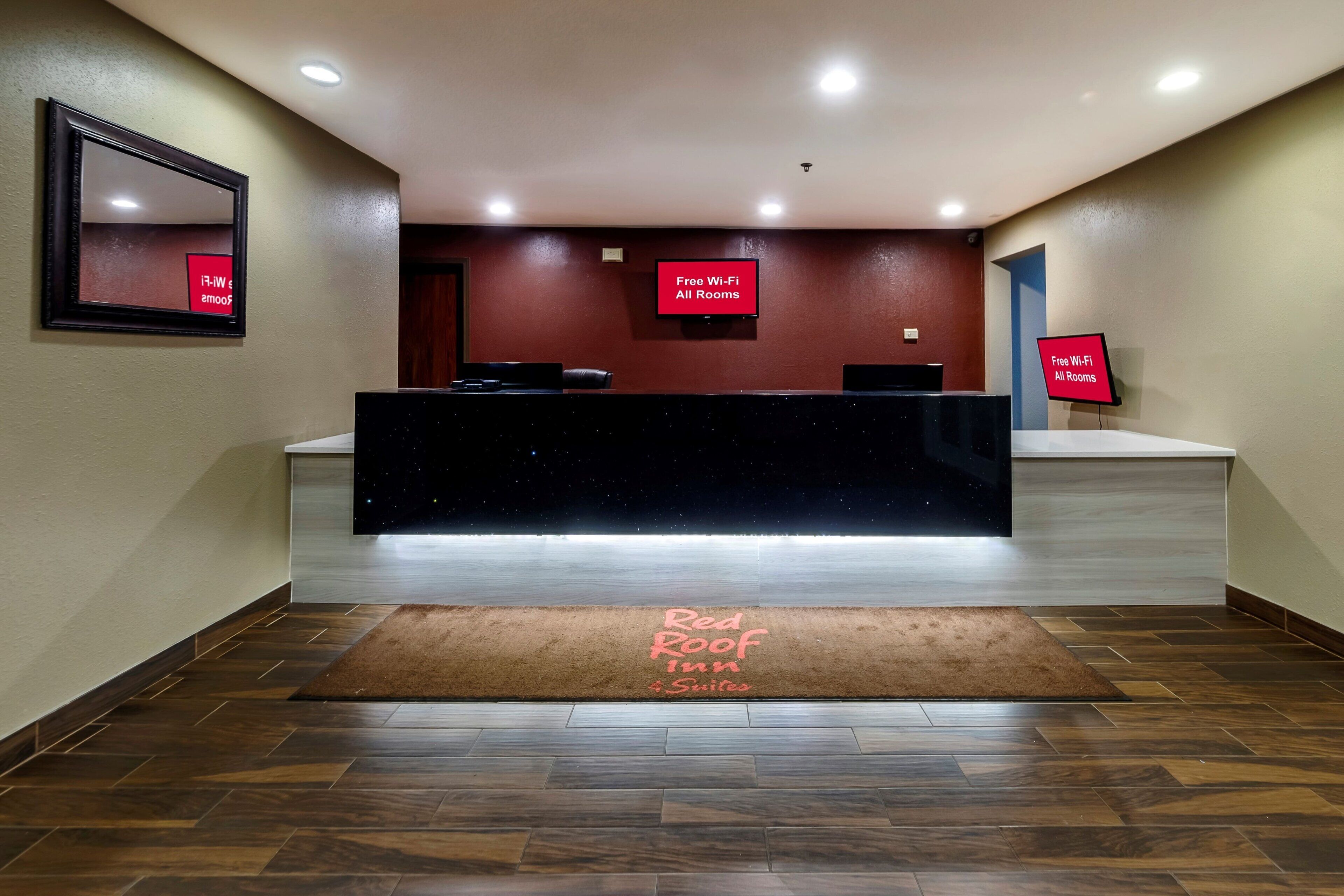 Zona de recepción de un hotel con mostrador, un cartel que indica Wi-Fi gratuito y una vista nocturna estrellada en la pared.