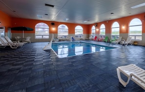 Una piscina interior con múltiples sillones de descanso y vistas al exterior a través de amplias ventanas.