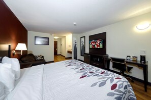 Una habitación de hotel con una cama grande, un escritorio, un televisor y una lámpara.