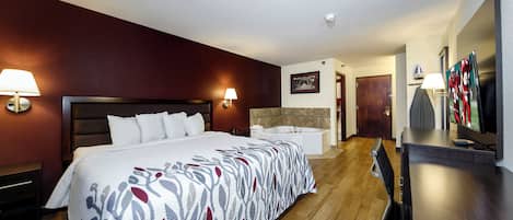 Een hotelkamer met een groot bed, een bureau, een televisie en een badkamer.