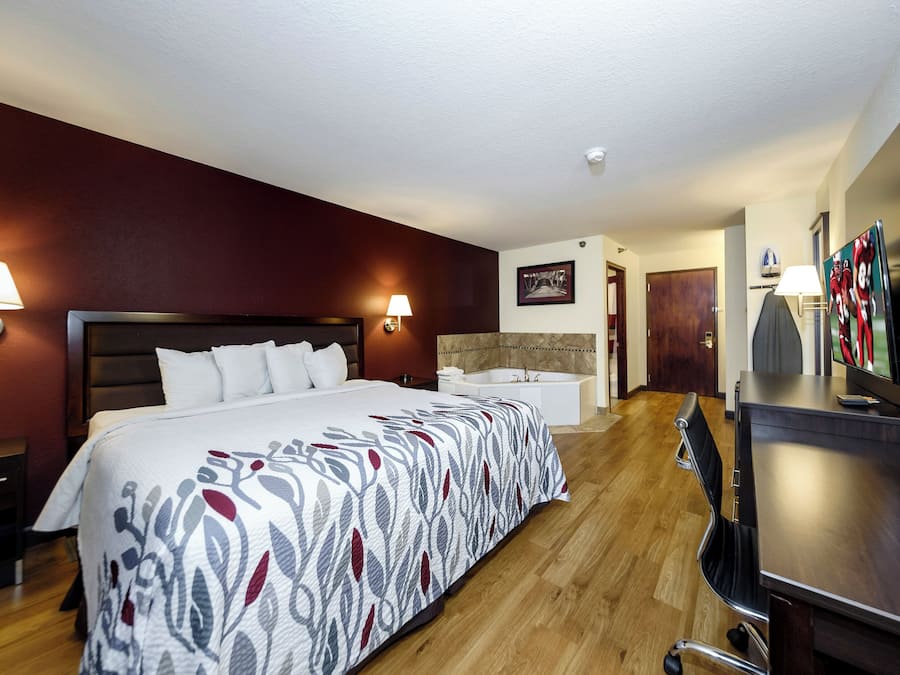 A hotel room with a large bed, a desk, a television, and a bathroom.