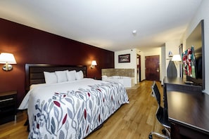Una habitación de hotel con una cama grande, un escritorio, un televisor y un baño.
