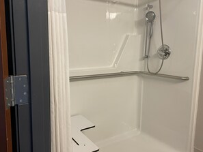 Un baño con ducha, una puerta blanca y un picaporte de metal.