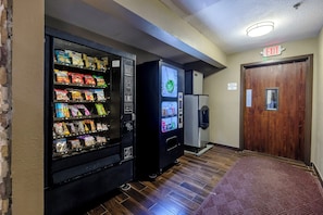 A vending machine with snacks and a water dispenser in a hallway.