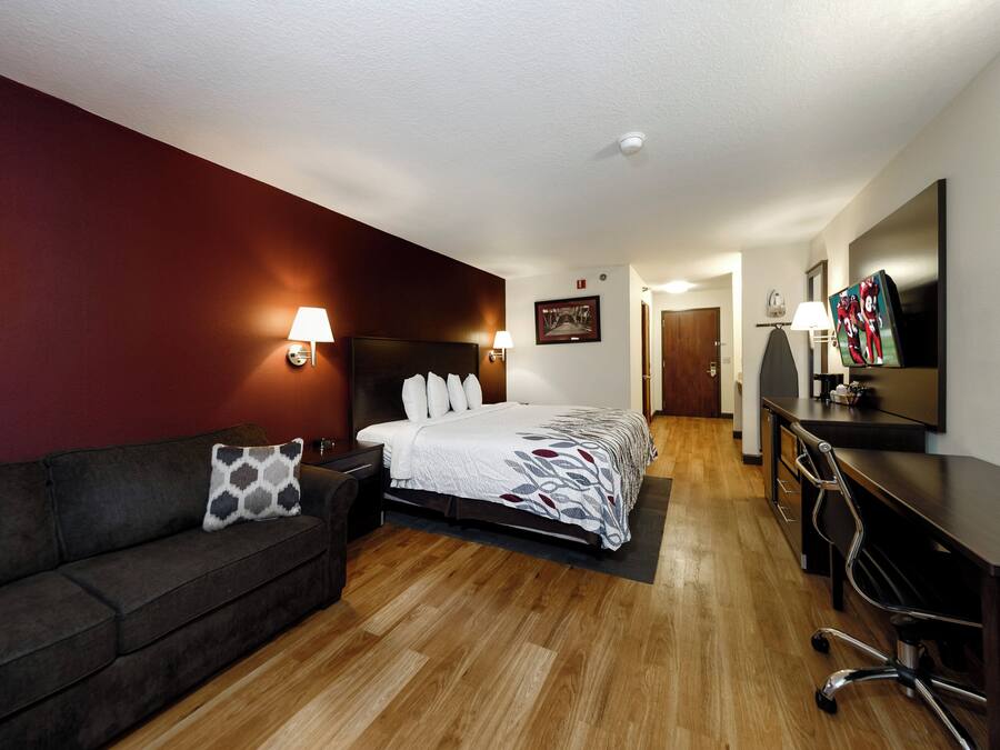 Een hotelkamer met een bed, bureau, stoel, bank en televisie.