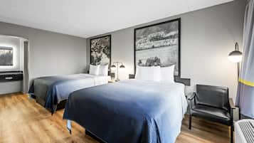 Una habitación de hotel con dos camas, una silla, un escritorio y una ventana.