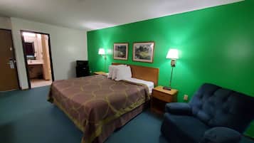 A hotel room with a bed, two bedside lamps, a chair, and two framed pictures on the wall.