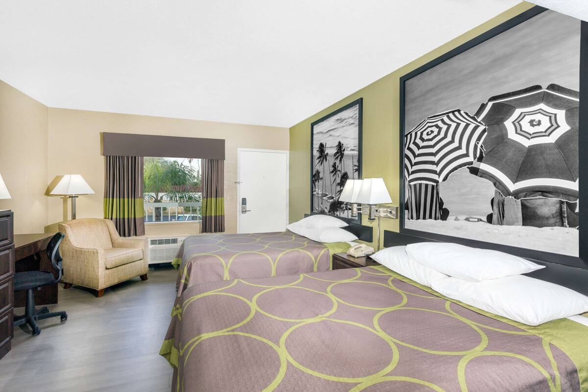 Une chambre d’hôtel avec un lit, un bureau, une chaise et deux tableaux accrochés au mur.