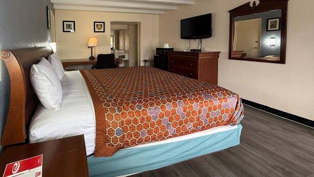 A hotel room with a large bed, a desk with a chair, a dresser, a flat-screen TV, and a mirror on the wall. - Econo Lodge Galax (Galax)