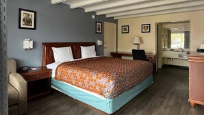 A hotel room with a large bed, a nightstand, a chair, a desk, and a mirror. - Econo Lodge Galax (Galax)