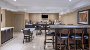 Een moderne keuken met een centraal eiland, barkrukken en een flatscreen televisie aan de wand.