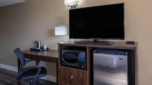 Een hotelkamer met een flatscreen televisie, een magnetron, een minibar, een bureau en een stoel.