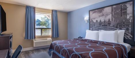 Ein Hotelzimmer mit einem großen Bett, einem Schreibtisch, einem Stuhl, einem Fenster mit Vorhängen und einem Wandgemälde mit Stadtansicht.