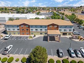 A multi-story hotel with a parking lot, a covered outdoor seating area, and a view of the surrounding neighborhood.