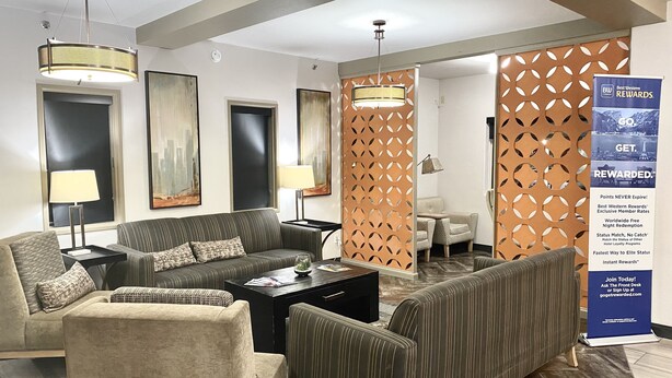 A modern hotel lobby with a sofa set, a coffee table, and a decorative partition. - Best Western Plus The Four Corners Inn (Farmington)